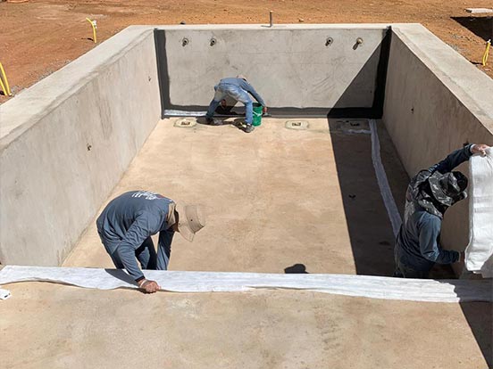 Aplicação do Revest em piscina de concreto com véu de poliéster — manta asfáltica líquida durante a obra