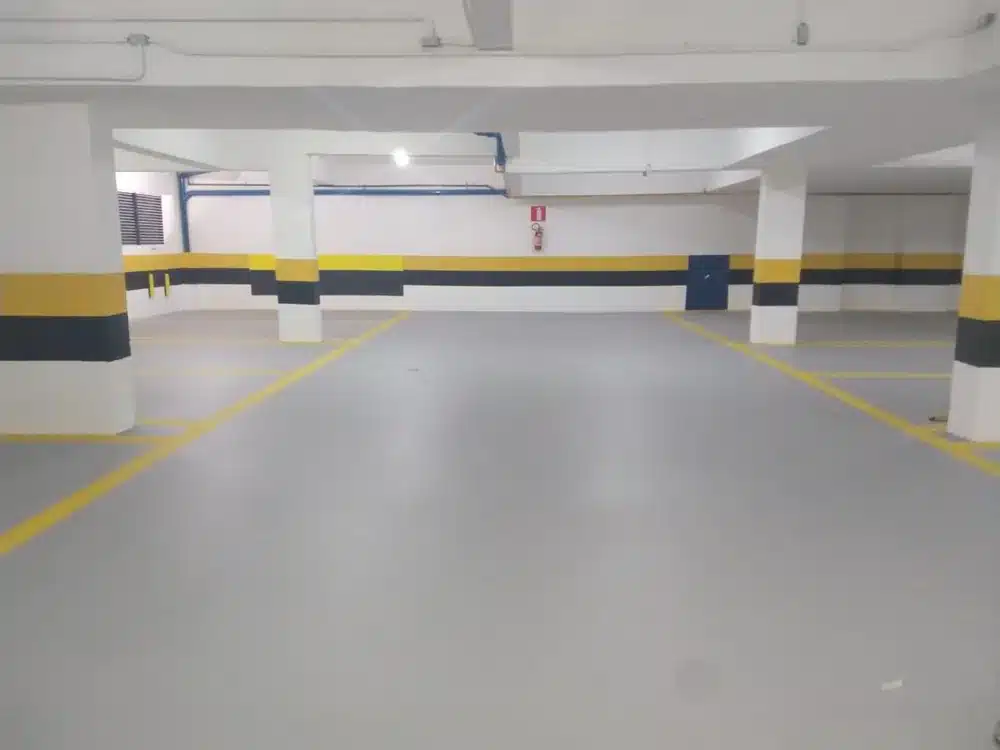 Estacionamento do Edifício Zodíacos com Sistema Parking 3.0: piso cinza e demarcação amarela